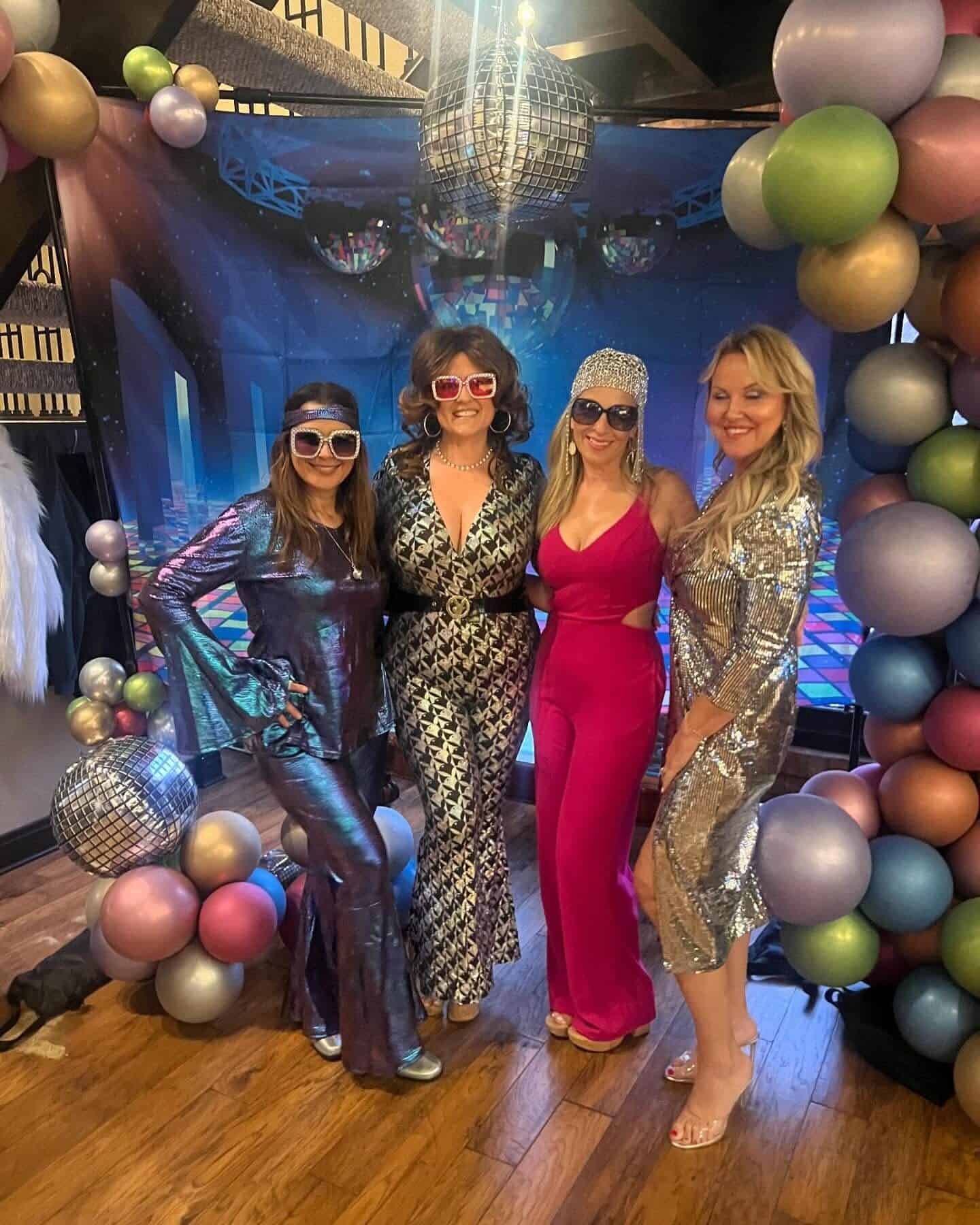 Four guests in 1970s disco outfits at the themed selfie station