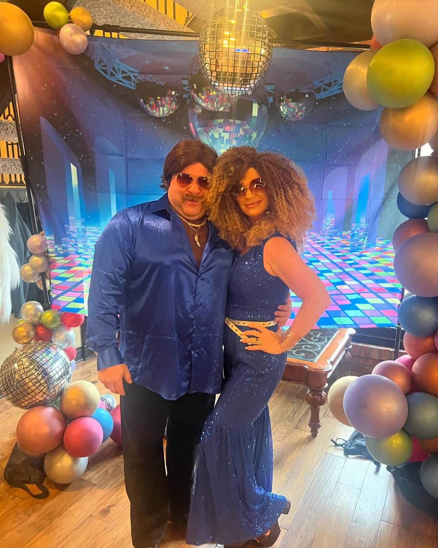 Two guests in blue disco costumes at the themed selfie station