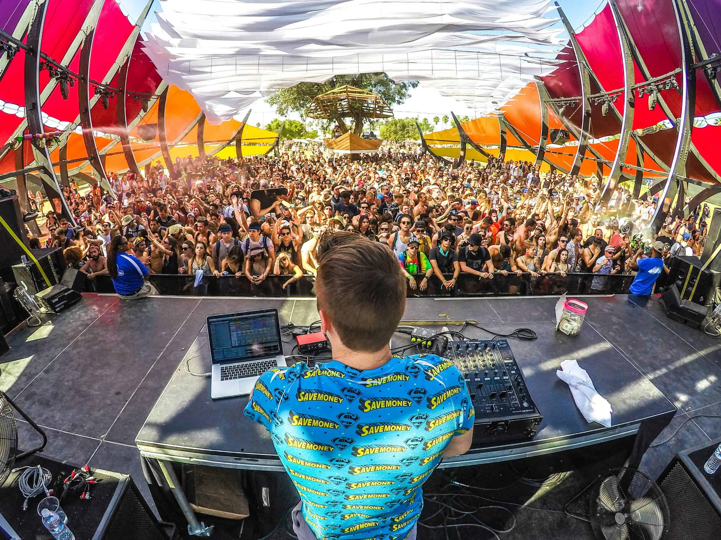 DJ performing on stage for a large outdoor festival crowd