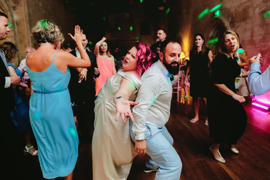 Guests dancing together under green event lighting